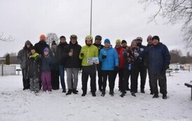 Grupa szesnanstu os&oacute;b stojąca z kiliszkami szampana na zaśniezonej ziemi