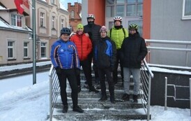 Sześciu mężczyzn w zimowych strojach rowerowych stojących na stoniach schod&oacute;w