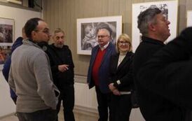 Sześć os&oacute;b stojących w pomieszczeniu, na ścianach kt&oacute;rego wiszą fotografie