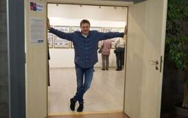 Mężczyzna stojący w otwartych drzwiach z rękoma opartymi o framugę