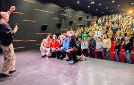 Dwie kobiety i trzech mężczyzn na scenie pozujących do wsp&oacute;lnej fotografii z ludźmi na widowni