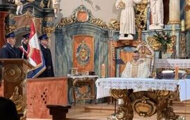 Ksiądz za ołtarzem i strażacki poczet sztandarowy