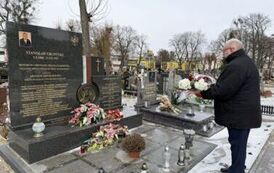 Mężczyzna stojący z kwiatami przed grobem Stanisława Grupińskiego