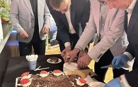 Czterech mężczyzn krojących i nakładających na talerzyki tort