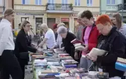 Grupa osób przeglądająca książki rozłożone na stołach