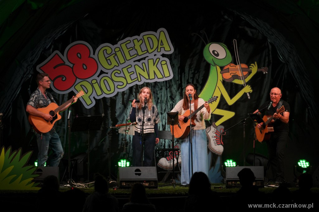 Dw&oacute;ch mężczyzn z&nbsp;gitarami i&nbsp;dwie kobiety, jedna z&nbsp;gitarą, druga z&nbsp;marakasą, na&nbsp;scenie 