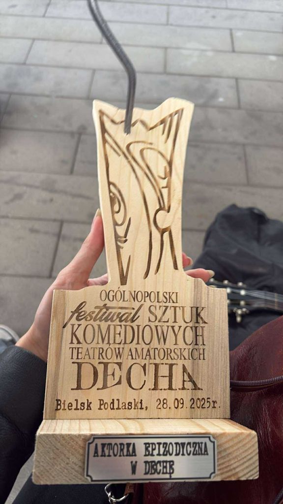 Statuetka w&nbsp;kształcie deski z&nbsp;wbitym gwoździem i&nbsp;wypalonym napisem Og&oacute;lnopolski Festiwal Sztuk Komediowych Teatr&oacute;w Amatorskich "Decha", Bielsk Podlaski 28.09.2025 r., aktorka wpizodyczna w&nbsp;dechę