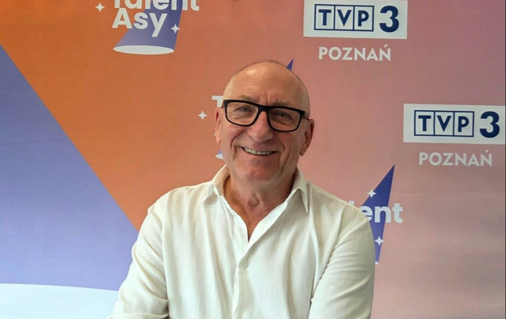 Fotografia portretowa mężczyzny na&nbsp;tle plansz z&nbsp;naspisem TVP3 Poznań oraz&nbsp;TalentAsy