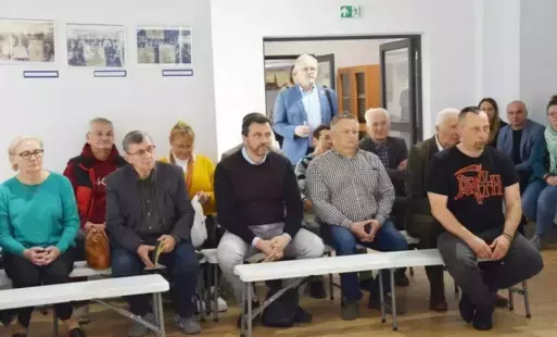 Grupa osob siedząca na ławkach