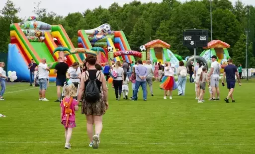 Dzieci z rodzicami zmierzający w stronę pneumatycznych zjeżdżalni
