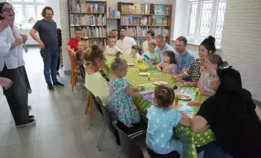 Uczestnicy warsztatów siedząc przy stole wykonują polecenia instruktorki