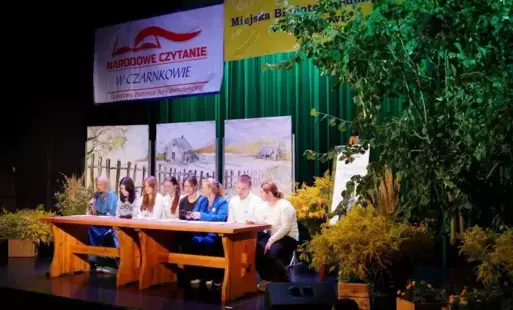 Młodzież siędząca za stołem czyta poezję Jana Kochanowskiego