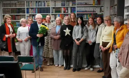 Mężczyzna z żółtymi kwiatami stający w towarzystwie jednego mężczyzny i trzynastu kobiet