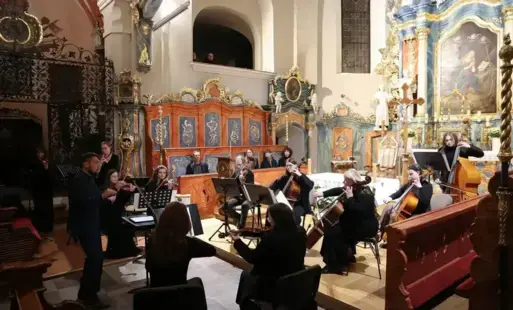 Muzycy siedzący z instrumentami na krzesłach przed ołtarzem