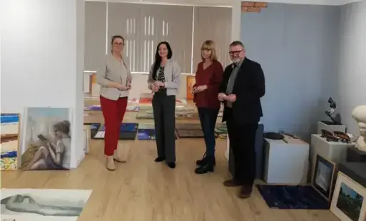 Trzy kobiety i jeden mężczyzna stojący w otoczeniu obrazów i rzeźb