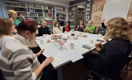 Kobiety siędzące na krzesłach wokół zestawionych stołów