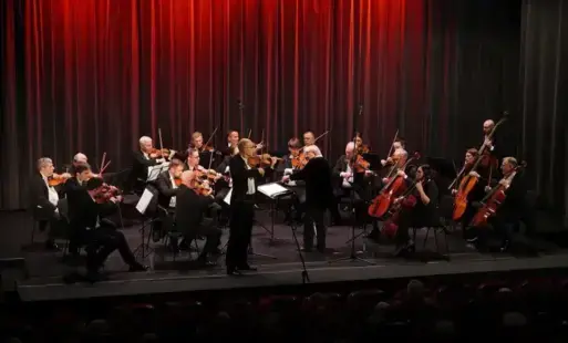 Orkiestra z dyrygentką i solowym skrzypkiem podczas występu