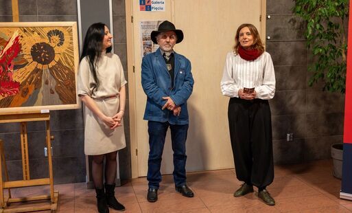 Mężczyzna stojący pomiędzy kobietami, obok kolorowy obraz
