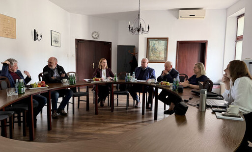 Trzy kobiety i czterech mężczyzn siedzących przy owalnym stole