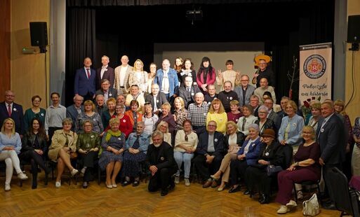 Grupa osób ustawiona na tle sceny do wspólnego zdjęcia