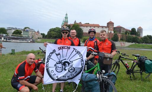 Rowerzyści z banerm Rowerowej Sekcji Turystycznej w Czarnkowie na tle Wisły i Wawelu